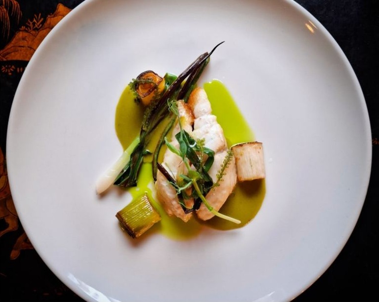 Artur’s plated seafood dish with green sauce and vegetables